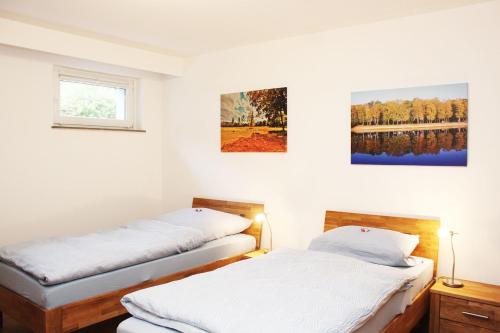 two beds in a room with two paintings on the wall at Ferienwohnung Kastanienblick in Uelzen