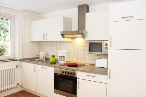 a kitchen with white cabinets and a white refrigerator at Ferienwohnung Kastanienblick in Uelzen