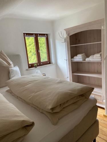 a white bedroom with a large bed and a window at Bergliebe in Weitnau
