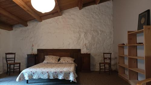 a bedroom with a bed in a room with chairs at Logis de Rocles in Rocles