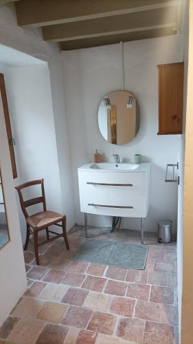 a bathroom with a sink and a mirror and a chair at Logis de Rocles in Rocles