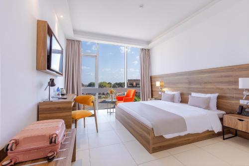 ein Hotelzimmer mit einem Bett und einem Schreibtisch mit einem Koffer in der Unterkunft Seen Ran Hotel Bouake in Bouaké