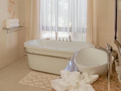 a white bathroom with a tub and a window at Tuli House in Harare