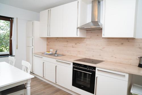 a kitchen with white cabinets and a stove top oven at Ferienwohnung BEA 1 in Rabenkirchen-Faulück