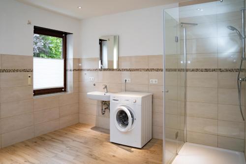 a bathroom with a washing machine and a sink at Ferienwohnung BEA 1 in Rabenkirchen-Faulück