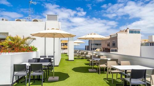 an outdoor patio with tables and chairs and umbrellas at URBANSEA Las Palmas in Las Palmas de Gran Canaria