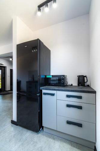 a kitchen with a black refrigerator and a white cabinet at Morski Resort in Ustka