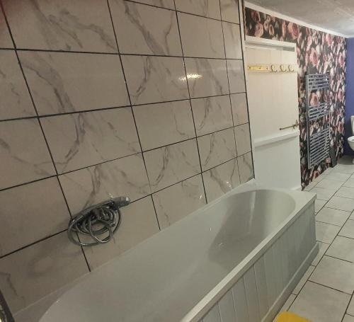 a bath tub in a bathroom with a marble wall at Maison des Roses in Béalencourt