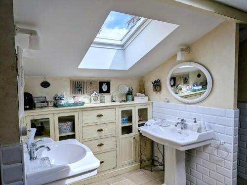 a bathroom with two sinks and a skylight at La Grange d'Hélène in Cholet