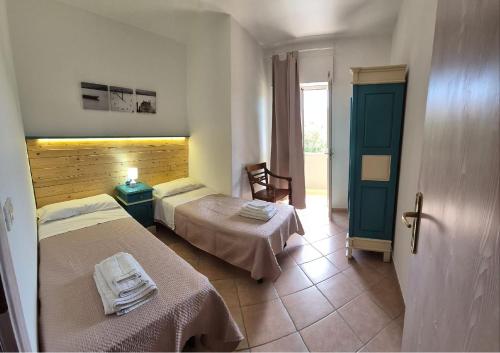 a hotel room with two beds and a door at Le Palme Holidays in Palmadula
