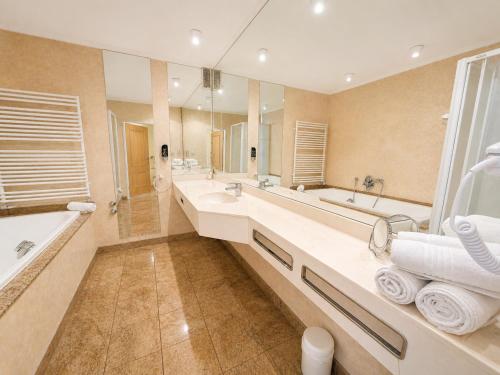 a bathroom with two sinks and a tub and a large mirror at Seehotel Schwanenhof in Mölln