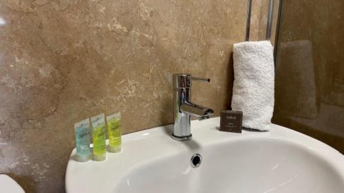 a bathroom sink with a faucet and three drinking glasses at The New Inn in Oswestry