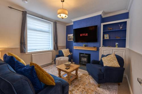 a living room with blue walls and a tv at Cosy Peak District Cottage Walk to Town Centre in Fairfield