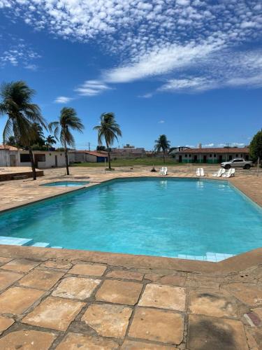 a blue swimming pool with palm trees in the background at Carranca Grande Hotel in Xique-Xique