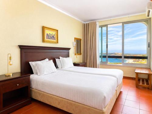a bedroom with a large bed and a large window at Aparthotel Navigator in Sagres