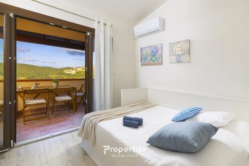 a bedroom with a bed and a balcony with a table at Il terrazzo sulla duna 5 by Propertize in Marrùbiu