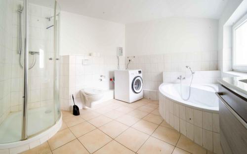 a bathroom with a shower toilet and a washing machine at Ferienwohnung Kaufmann 3 in Rabenkirchen-Faulück