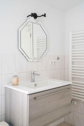a white bathroom with a sink and a mirror at Ferienwohnung Kaufmann 3 in Rabenkirchen-Faulück