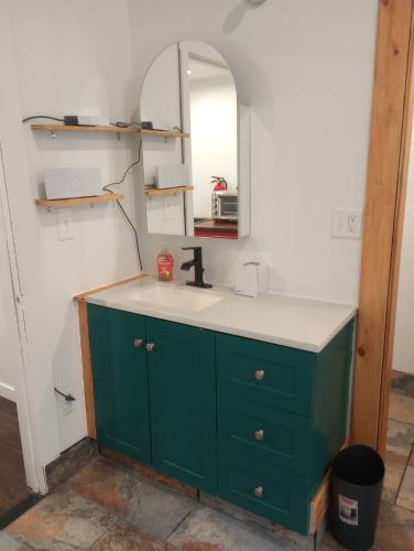 a bathroom with a green sink and a mirror at Cozy Container in Soldotna