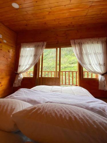a bedroom with two beds and windows in a cabin at La Cima Bachué in Ubaque