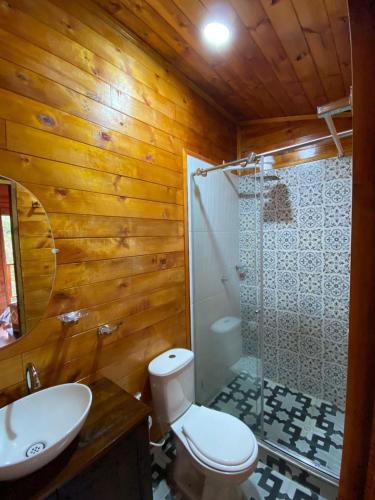 a bathroom with a toilet and a shower with wooden walls at La Cima Bachué in Ubaque
