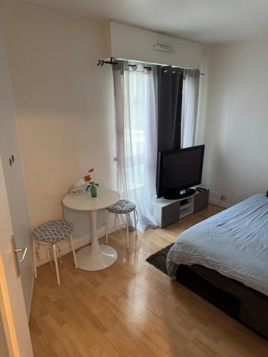 a bedroom with a bed and a table and a tv at Charmant studio à Paris La Défense in Courbevoie
