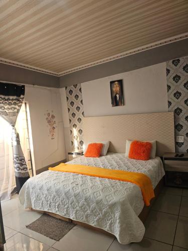 a bedroom with a large bed with orange and white sheets at Turfloop guest house in Ga-Mothapo