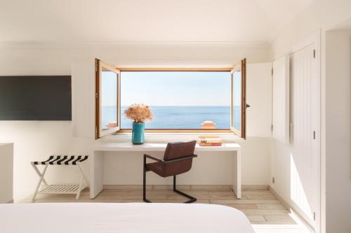 a bedroom with a desk and a window with the ocean at Casa Pôr do Sal - Boutique Suites, Sea Views & Heated Pool in Luz