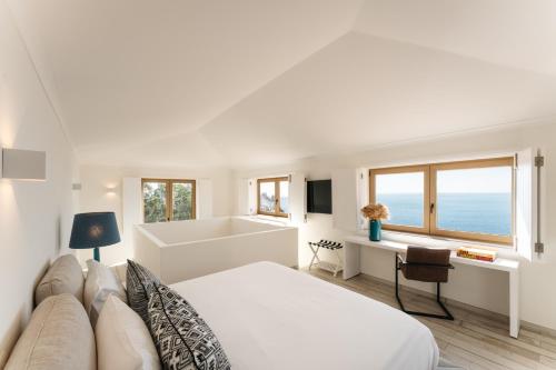 a white bedroom with a bed and a bath tub at Casa Pôr do Sal - Boutique Suites, Sea Views & Heated Pool in Luz