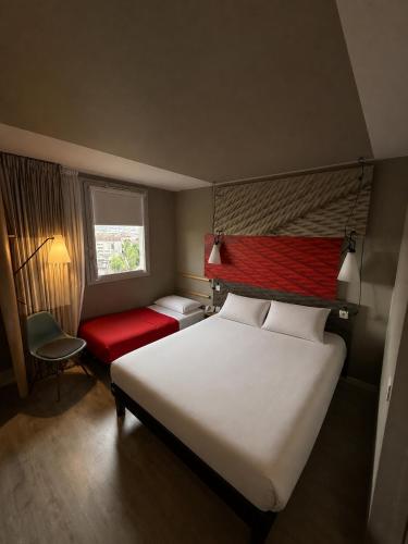 a hotel room with a bed and a red chair at Hotel ibis Dijon Centre Clemenceau in Dijon