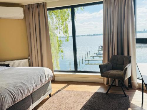 a bedroom with a bed and a chair and a large window at Weromerie Premium Hotel and Apartment in Wormer