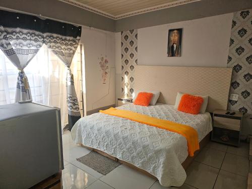 a bedroom with a bed with orange pillows and a television at TURFLOOP guest house in Mankweng