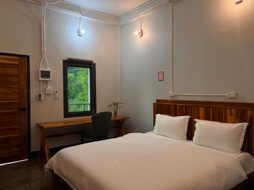 a bedroom with a bed and a desk and a window at Valley Villa Hotel in Nongkhiaw