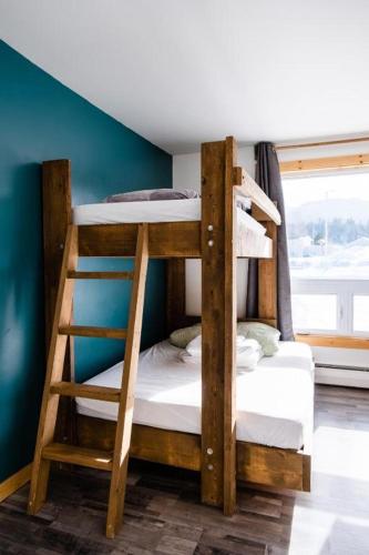 two bunk beds in a room with a window at Auberge de Jeunesse Le Camp De Base in LʼAnse-Saint-Jean