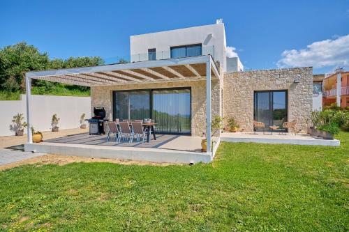 a house with a patio with a table and chairs at Arillas Villas in Arillas
