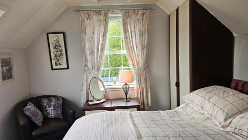 a bedroom with a bed and a chair and a window at Argyllholidaycottage Loch Awe in Eredine