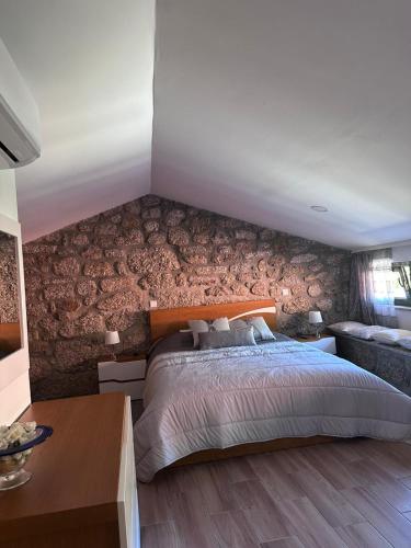 a bedroom with a large bed and a brick wall at Quinta do Assento in Louredo