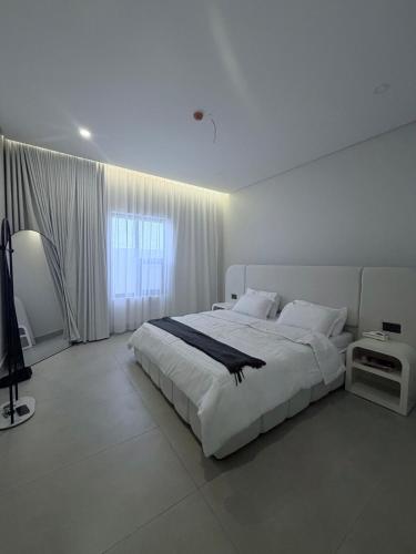 a white bedroom with a large bed and a window at AURA Stay in Dammam