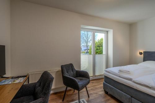 a bedroom with two chairs and a bed and a window at Johouse Zingst Johouse Zimmer 01 in Zingst