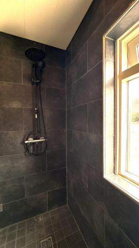 a bathroom with a shower with black tiles at Thorbrandsstadir Farm Holidays in Þorbrandsstaðir