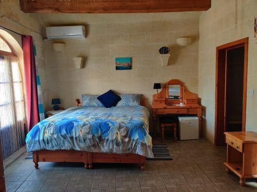 a bedroom with a bed and a desk and a mirror at Ta' Karkar Villa Bed and Breakfast in Xagħra