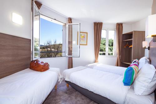 a hotel room with two beds and a window at Hôtel la Rotonde in La Croix-Valmer