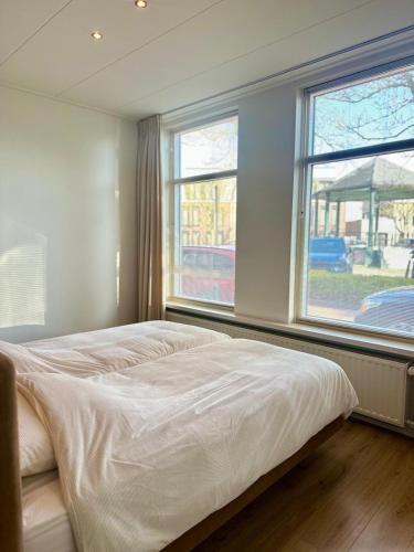 a bed in a room with two large windows at Het Kantoor in Philippine