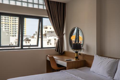 a bedroom with a bed and a desk with a mirror at Bluzen Hotel in Danang