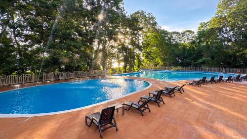 a large swimming pool with chairs and trees at Hotel Amazon by On Vacation in Leticia