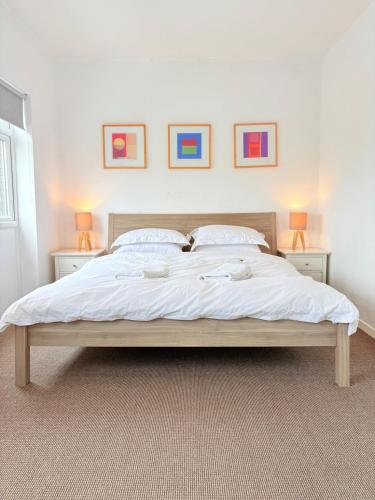a large bed in a bedroom with three pictures on the wall at Two Floor Flat in Town Center in Kenilworth