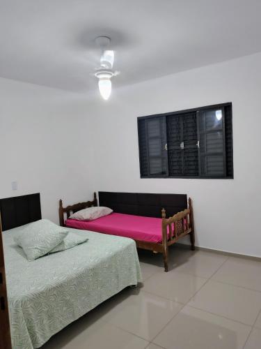 two beds sitting in a room with a window at Recanto do Tião in Itapira