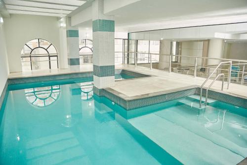 a swimming pool with blue water in a building at Miramar Hotel in Balneário Camboriú
