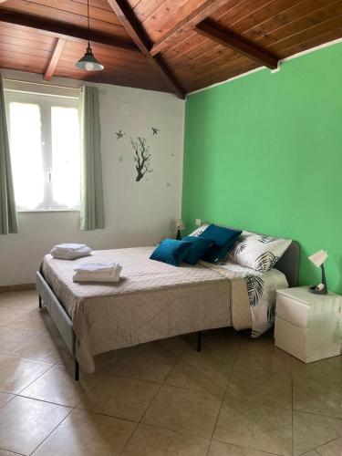 a bedroom with a bed with a green wall at L'Ulivo in Formia