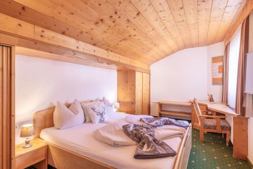 a bedroom with a bed and a desk in a room at Bergidyll & Hotel Trofana in Leutasch